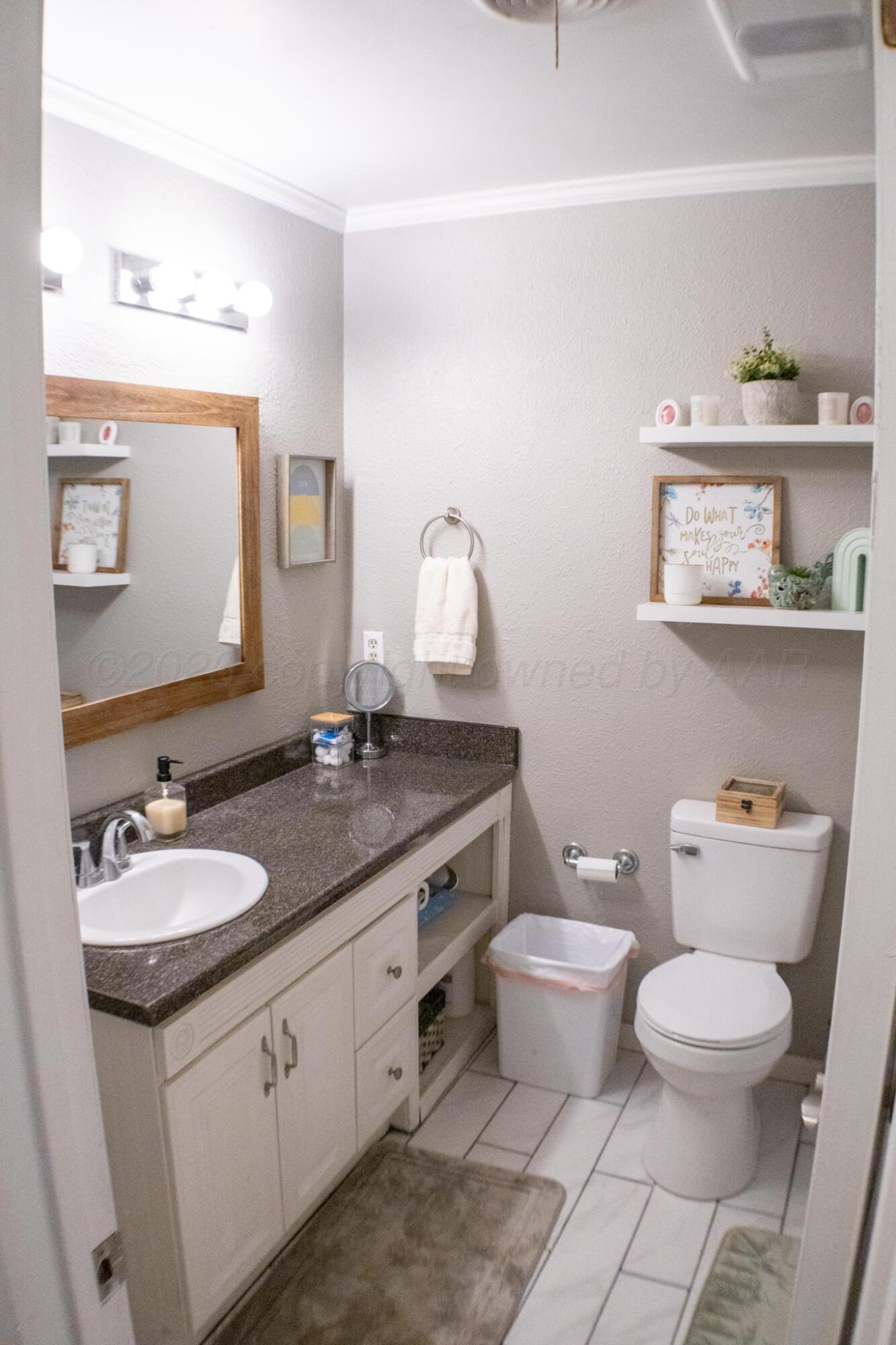 4504 Goodnight Trail Amarillo, TX 79109 - Photo 27 of 32 a bathroom with a granite countertop toilet sink and mirror