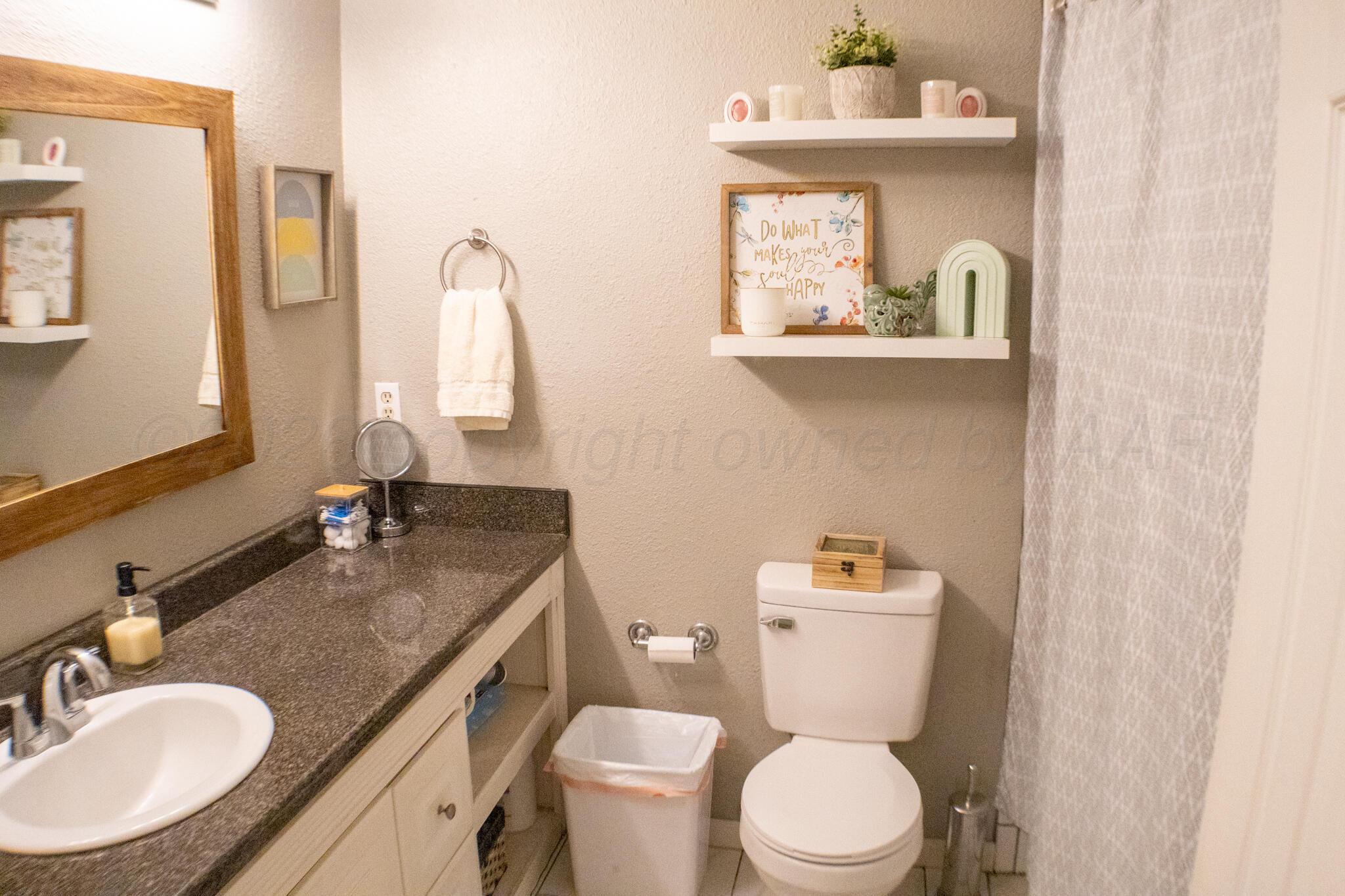 4504 Goodnight Trail Amarillo, TX 79109 - Photo 28 of 32 a bathroom with a granite countertop toilet sink and mirror