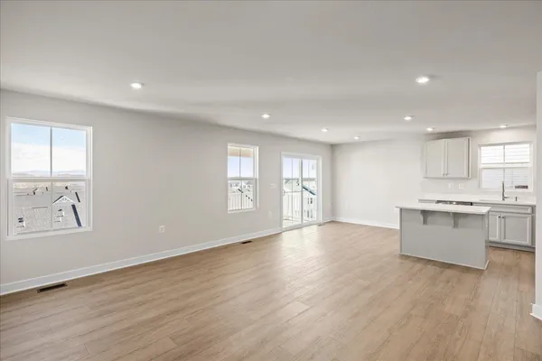 a view of an empty room with window and wooden floor