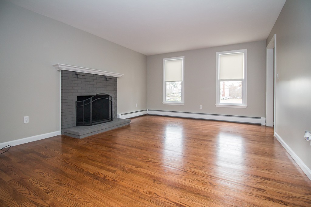5 McGuire Road Sutton, MA 01590 - Photo 6 of 22 an empty room with wooden floor fireplace and windows