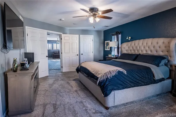 a spacious bedroom with a bed a couch and a flat screen television