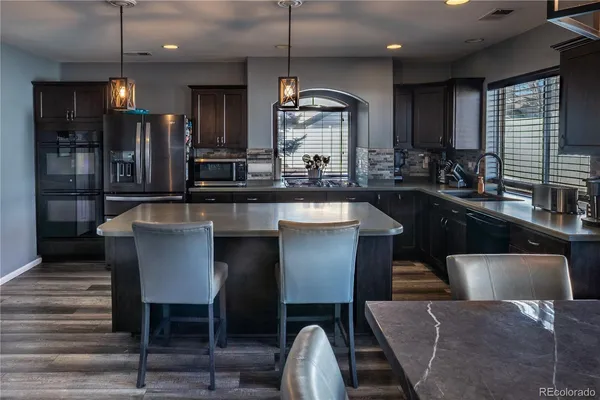 a kitchen with kitchen island granite countertop a table chairs sink refrigerator and microwave