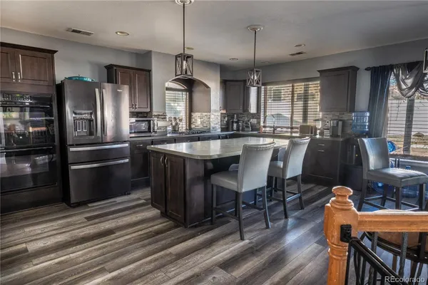 a kitchen with granite countertop a table chairs stove refrigerator and wooden floor
