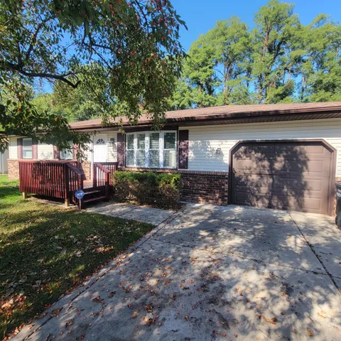 a view of a house with a yard plants and large tree