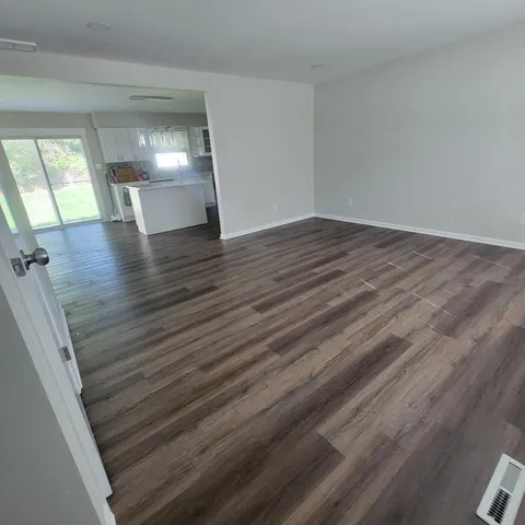 a view of empty room with wooden floor
