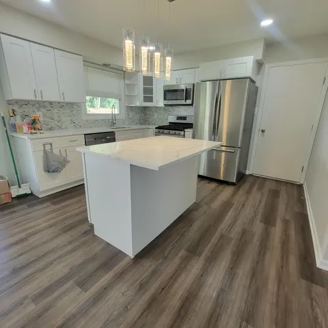 a kitchen with refrigerator and wooden floor
