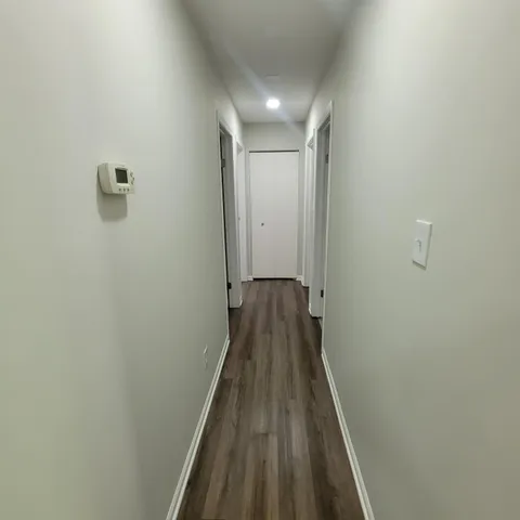 a view of a hallway with wooden floor and a bathroom