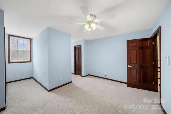 an empty room with windows and fan