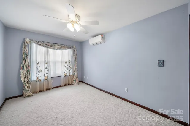 an empty room with chandelier fan and windows