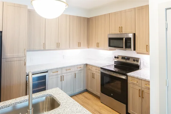 a kitchen with granite countertop a sink dishwasher stove and microwave with wooden floor