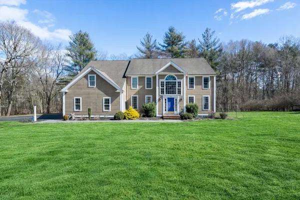 a front view of a house with a yard and trees