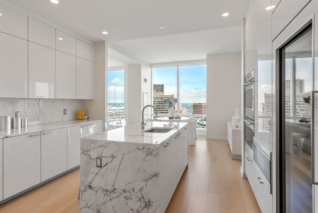 a large kitchen with kitchen island a large window a sink stainless steel appliances and cabinets