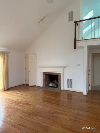 an empty room with wooden floor fireplace and windows