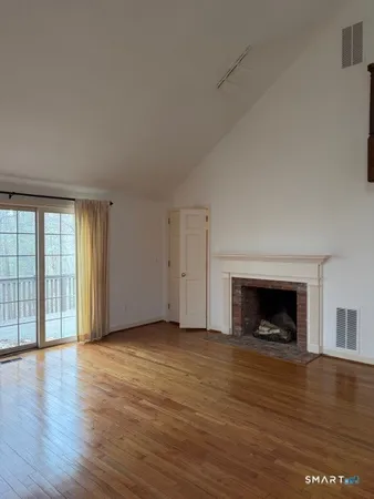 an empty room with wooden floor fireplace and windows