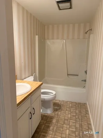 a bathroom with a granite countertop bathtub shower sink and toilet