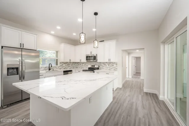 a large kitchen with kitchen island a stove a sink a refrigerator and a wooden floor