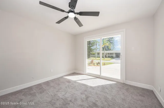 an empty room with windows and ceiling fan