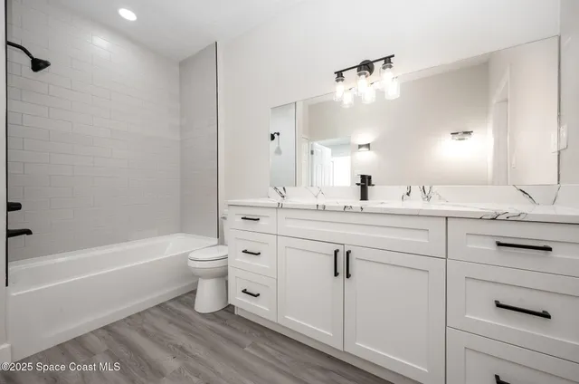 a bathroom with a double vanity sink a toilet mirror and bathtub
