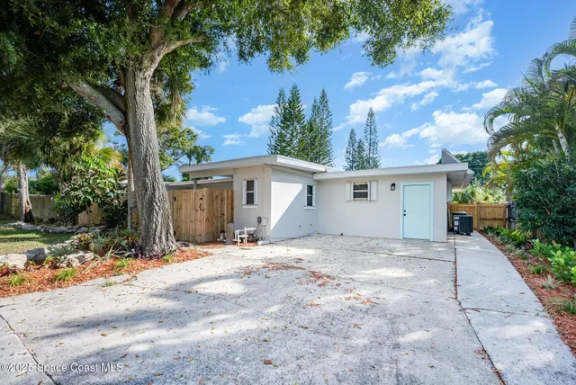 a view of house with yard and a large tree