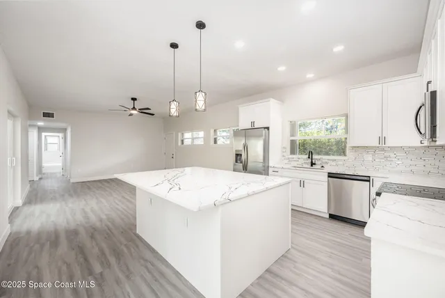 a kitchen that has a lot of white cabinets and wooden floor