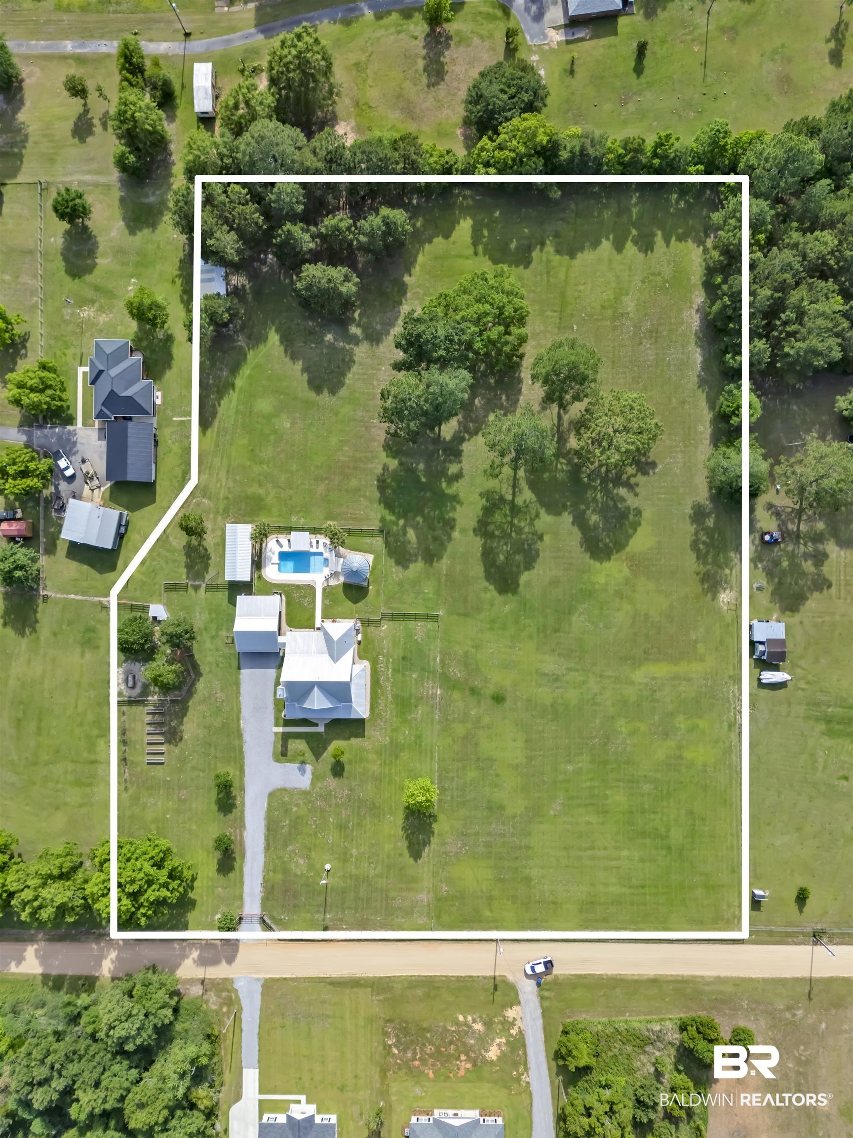 6576 Ranch Loop Road East Grand Bay, AL 36541 - Photo 38 of 39 Expansive parcel featuring a main residence with a light-colored roof, a rectangular swimming pool, and a gravel driveway