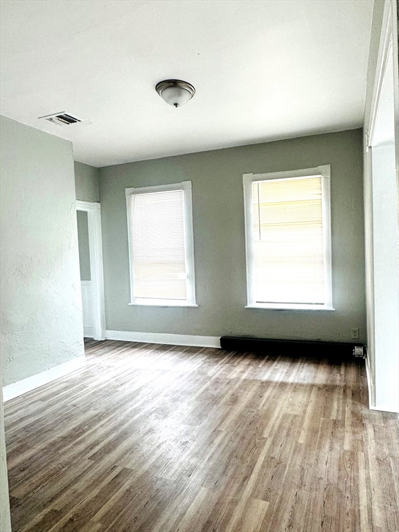 738 Central Street, Unit 2 Lowell, MA 01852 - Photo 2 of 11 a view of an empty room with wooden floor and a window
