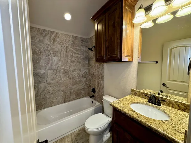 a bathroom with a granite countertop sink a toilet and a bathtub