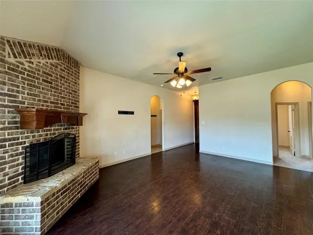 a view of an empty room with wooden floor and a fireplace
