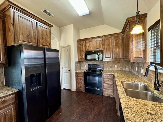 a kitchen with granite countertop a refrigerator stove and sink