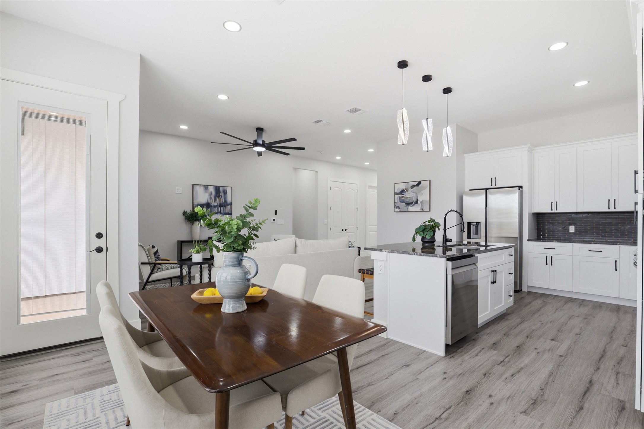 123 Los Robles Road Elgin, TX 78621 - Photo 8 of 21 Open-concept living space featuring wood-finish flooring, white cabinetry, stainless steel appliances, and a kitchen island with pendant lighting