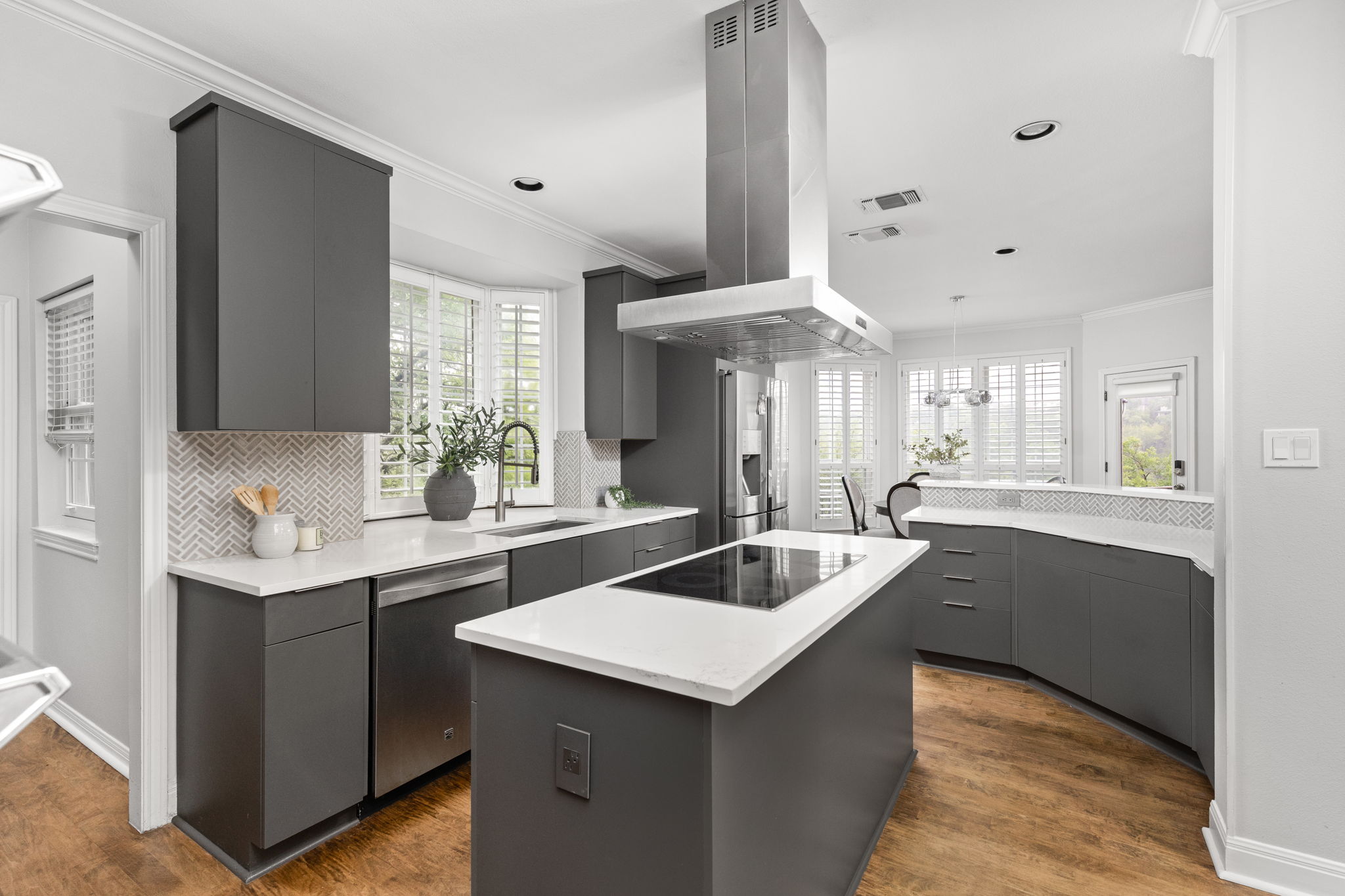 2807 Round Table Road Austin, TX 78746 - Photo 6 of 40 Modern kitchen featuring dark cabinetry, white countertops, stainless steel appliances, a center island with an integrated cooktop, and wood-finish flooring