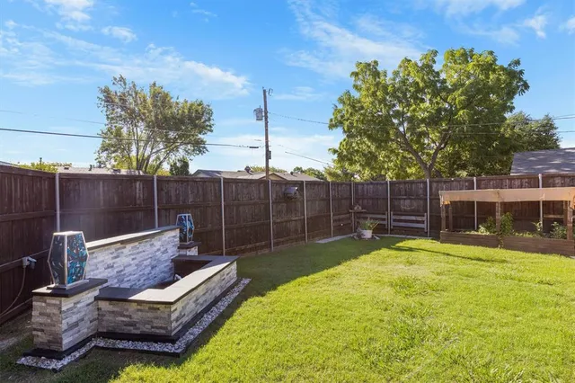 a view of a backyard with couches plants and wooden fence
