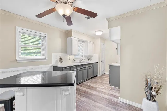 a large white kitchen with a window and wooden floor