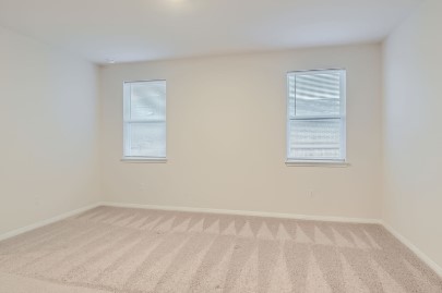 709 Iron Brg Road Georgetown, TX 78626 - Photo 7 of 11 A well-lit room awaits, featuring two windows with privacy blinds and soft, patterned carpeting.