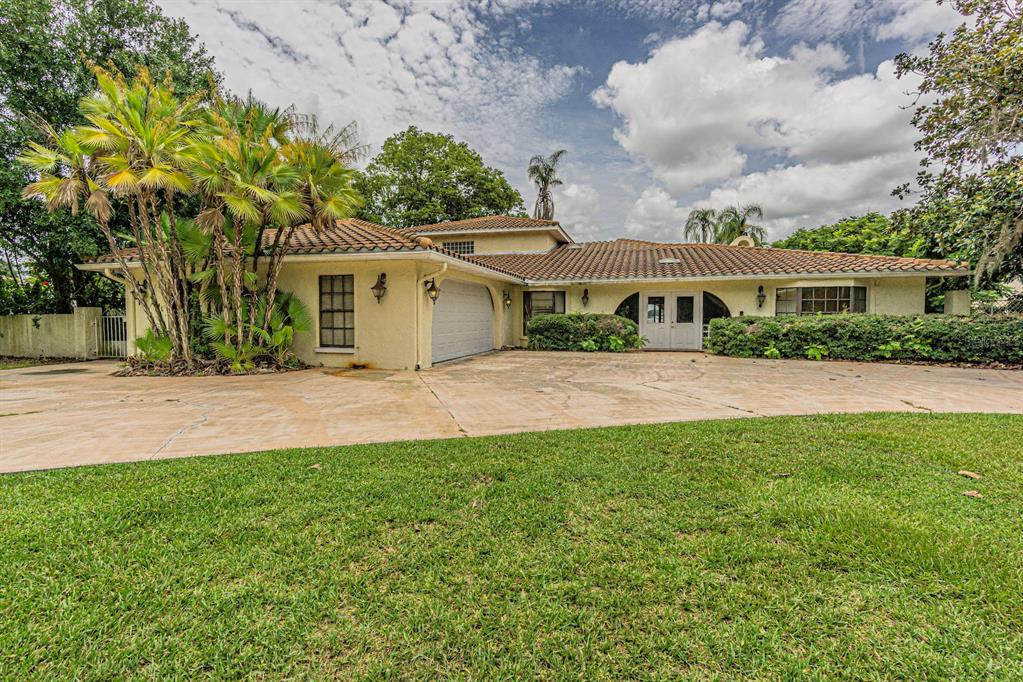 a view of house with a big yard and large trees