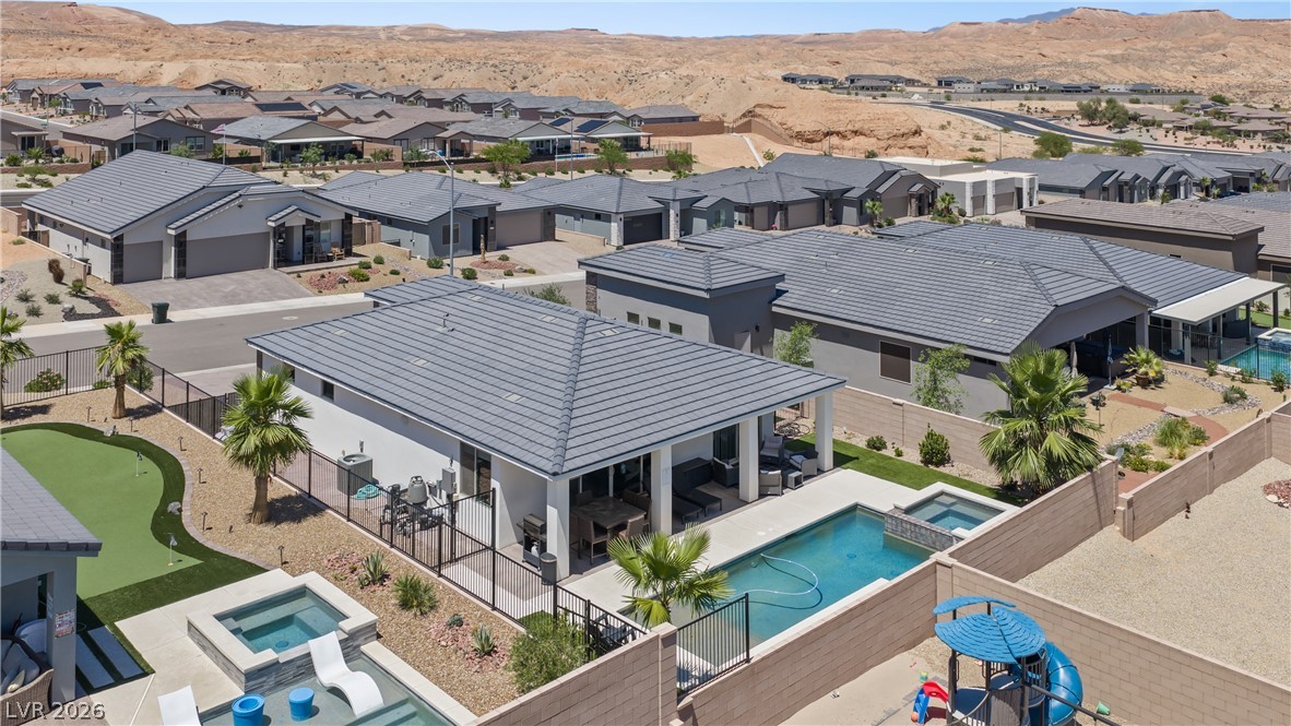 1436 Manassas Ridge Mesquite, NV 89027 - Photo 76 of 77 An aerial perspective reveals a modern desert community with multiple homes, each featuring a private pool and surrounding rugged hills.