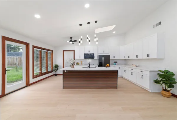 a large white kitchen with a large window and stainless steel appliances