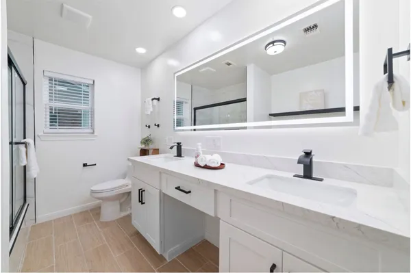 a bathroom with a sink a toilet a mirror and shower