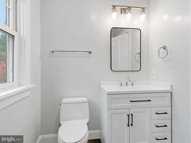 a bathroom with a toilet sink vanity and mirror