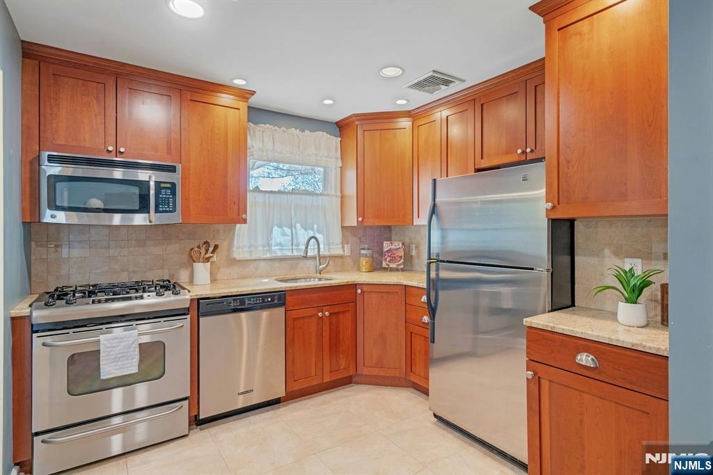 90 Arnot Place Paramus, NJ 07652 - Photo 9 of 32 a kitchen with stainless steel appliances a stove microwave and refrigerator