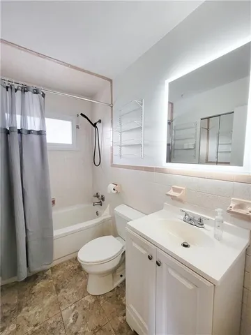 a bathroom with a toilet sink a mirror a bathtub and shower