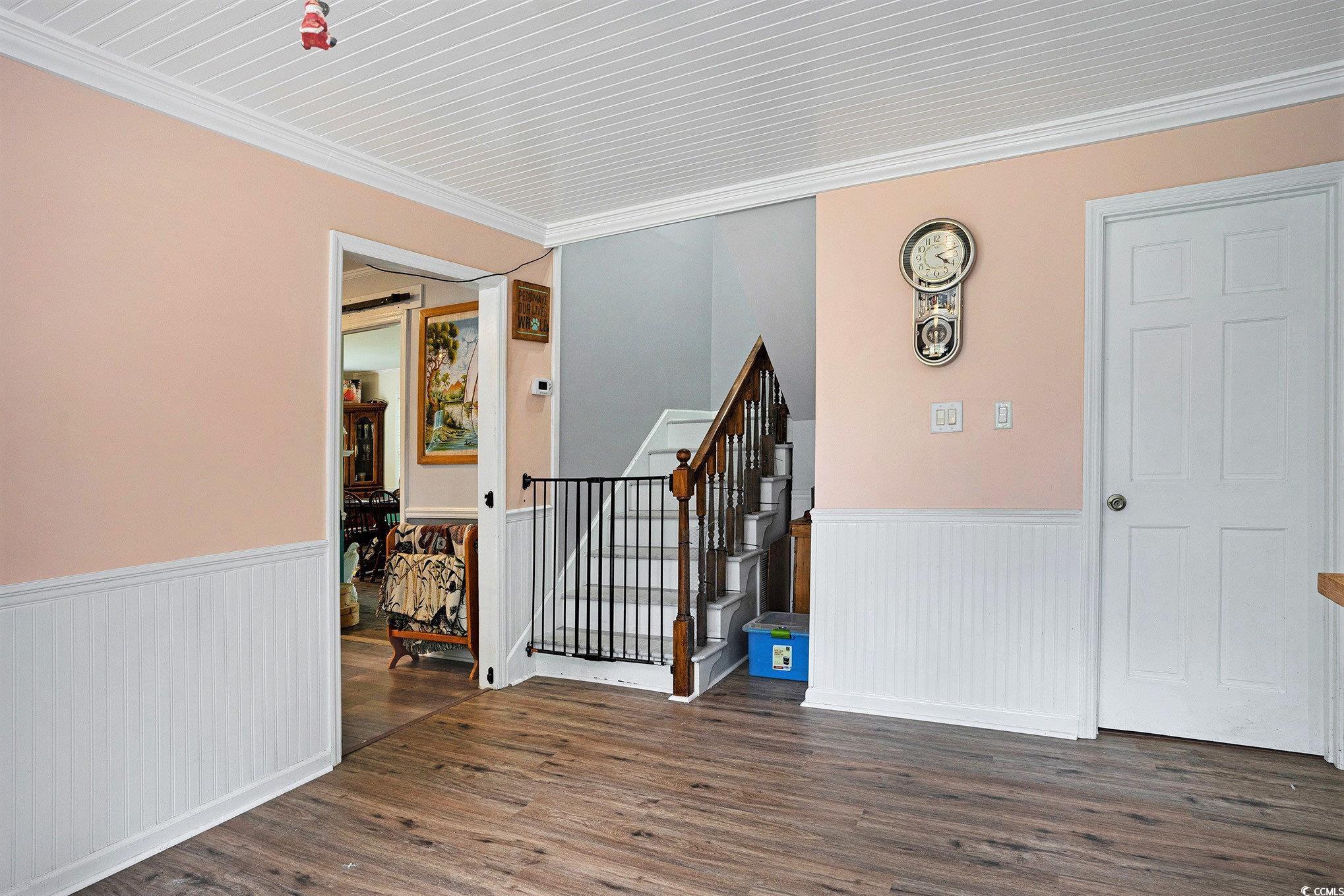 238 Robin Drive Georgetown, SC 29440 - Photo 12 of 31 Empty room featuring a wainscoted wall, wood finished floors, stairs, and ornamental molding