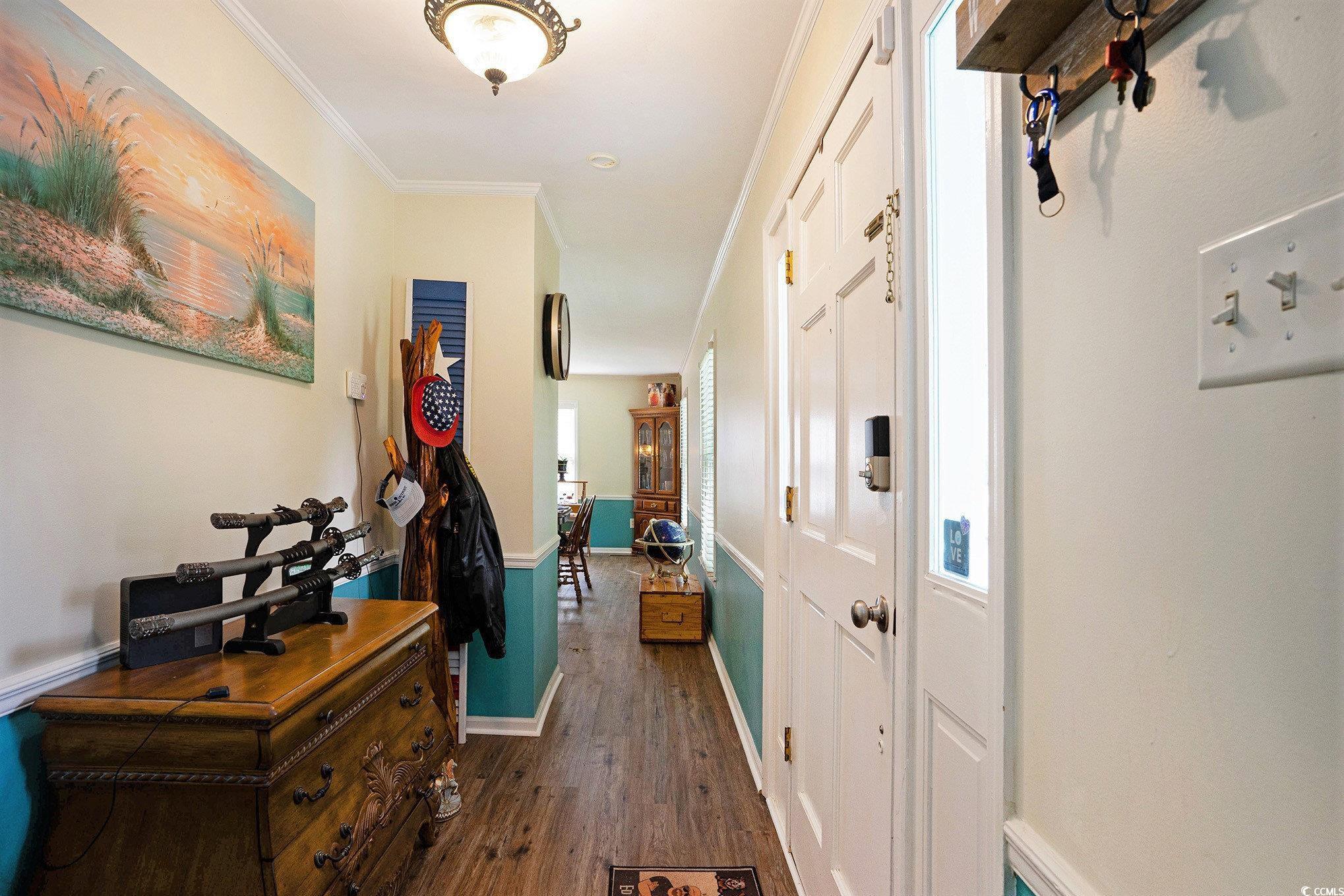Corridor with dark wood-style floors, baseboards, and ornamental molding