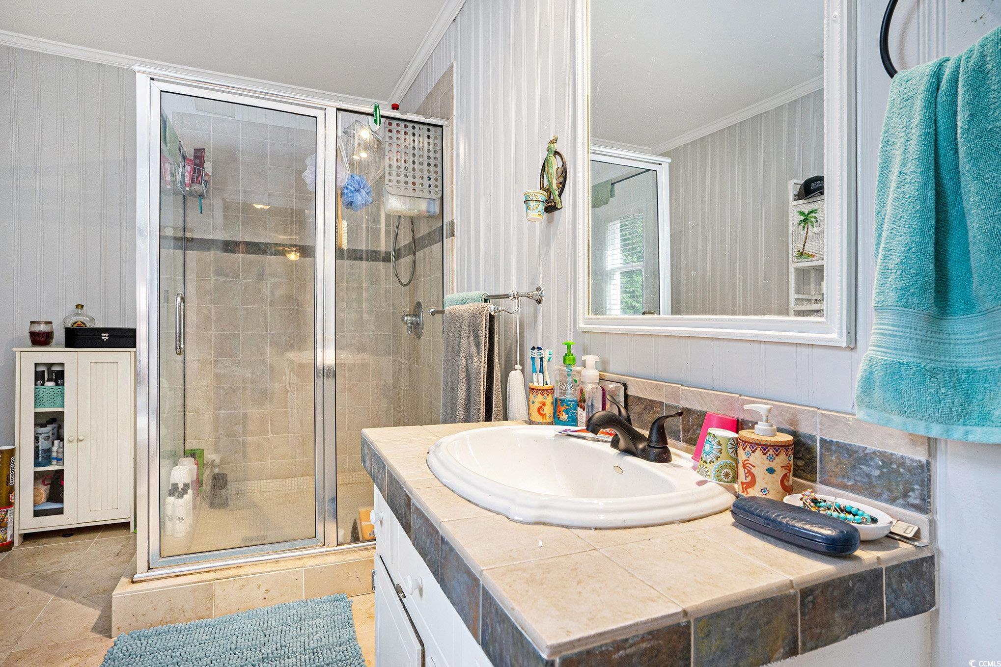 238 Robin Drive Georgetown, SC 29440 - Photo 24 of 31 Bathroom featuring ornamental molding, a stall shower, vanity, and stone finish floors