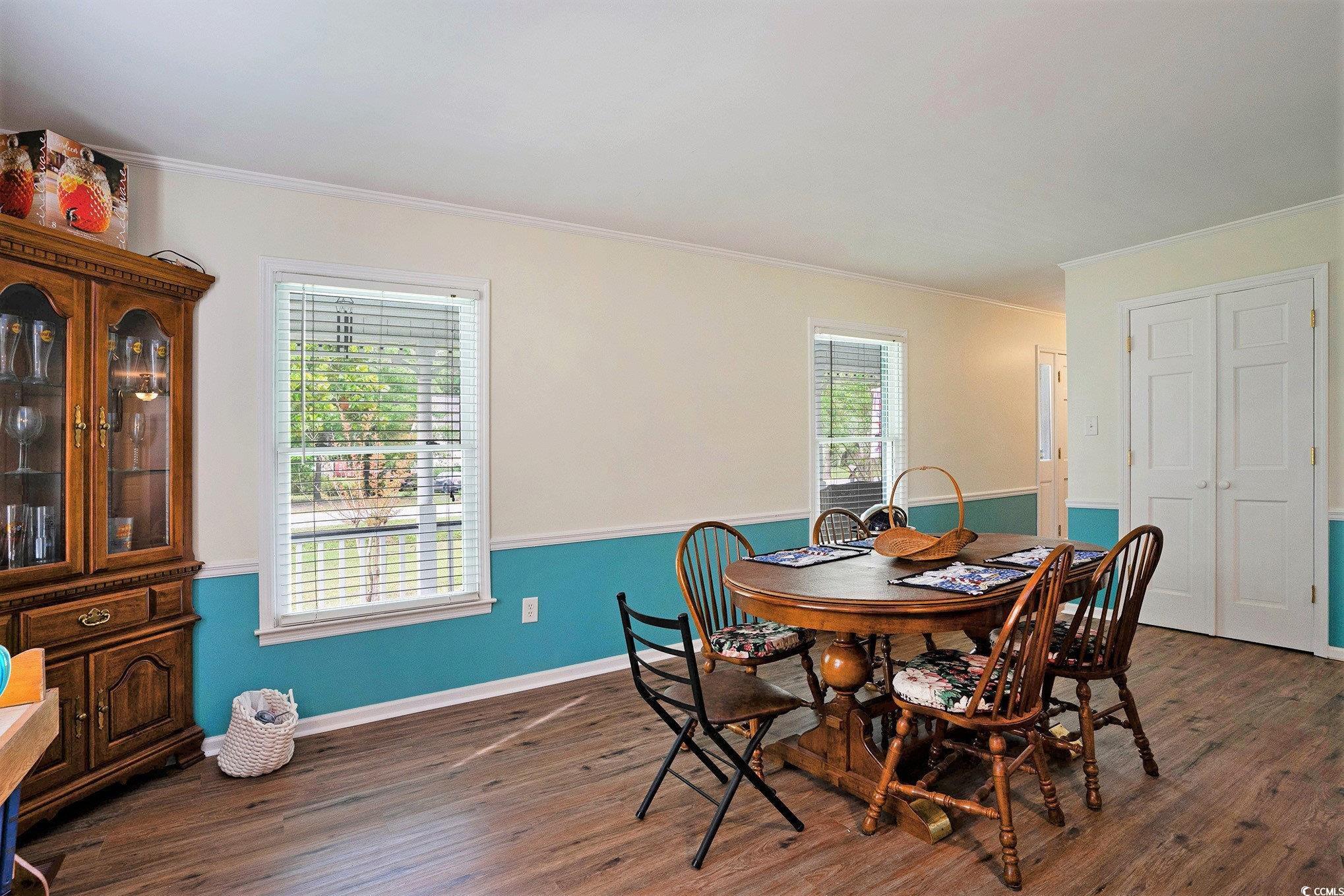 Dining room featuring ornamental molding, dark wood-type flooring, and baseboards