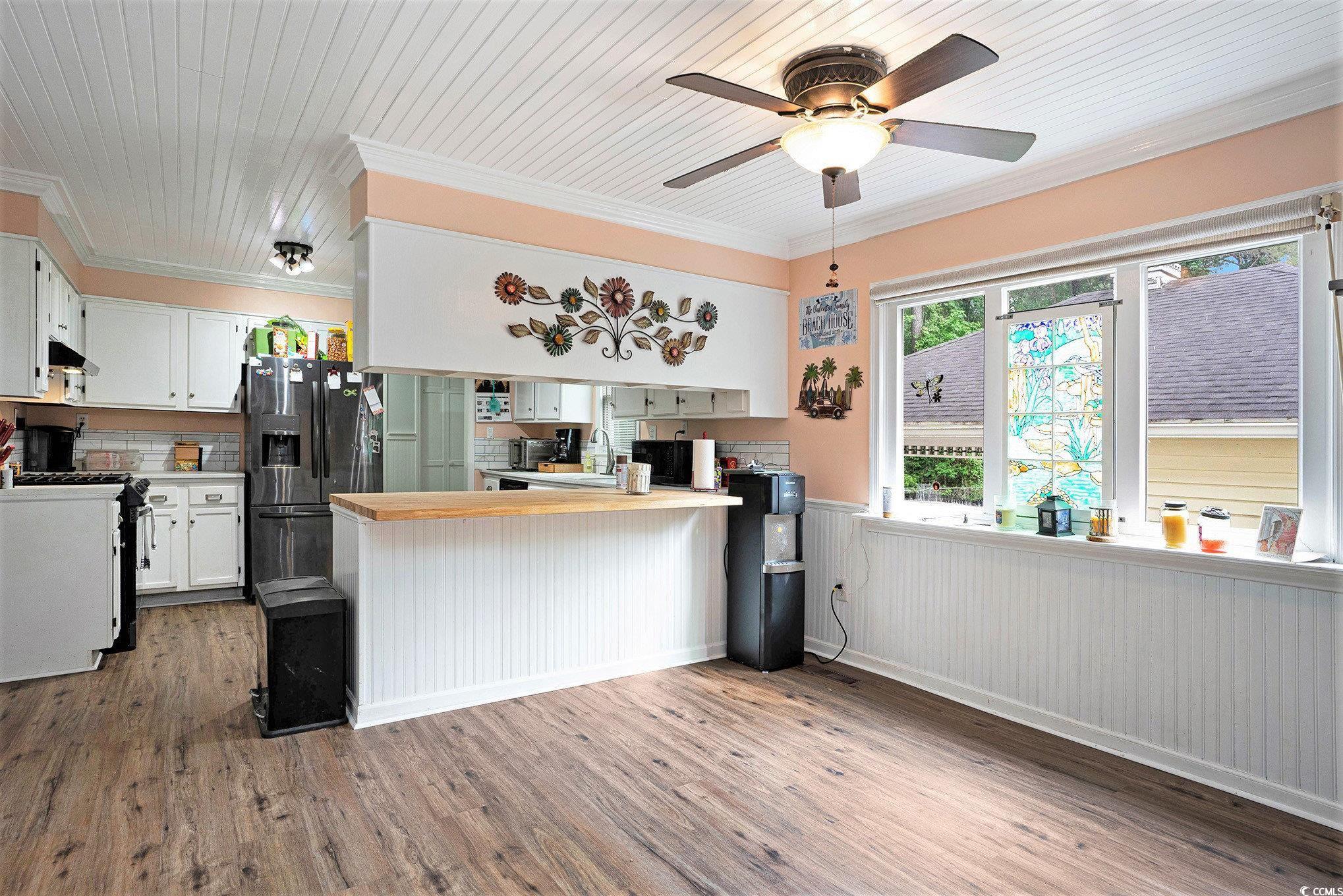 Kitchen with gas stove, fridge with ice dispenser, a peninsula, wood finished floors, and wainscoting