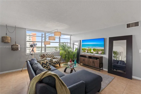 a living room with furniture a flat screen tv and floor to ceiling window