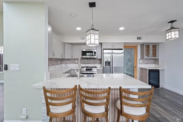 a kitchen with granite countertop kitchen island stainless steel appliances a dining table and chairs
