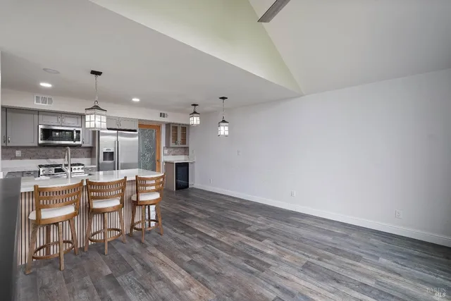 an open kitchen with wooden floor and stainless steel appliances
