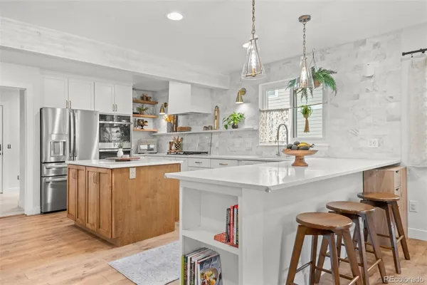 a kitchen with stainless steel appliances granite countertop a sink a stove a refrigerator cabinets and chairs